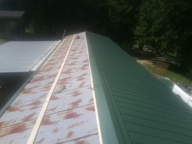 Old rusted panels beside newly installed green metal roofing — Wind Damage Roof Repair by Roofing Brothers in New Ipswich