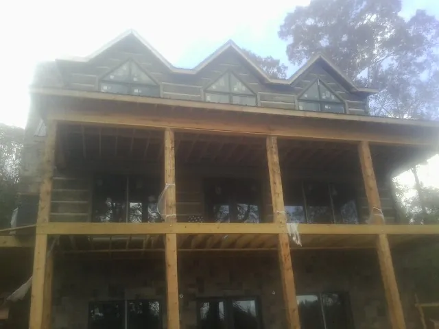 Dormers and porch framing on a large log home under construction — Roof Coating work by our crew in New Ipswich