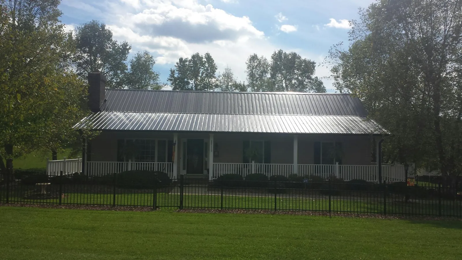 Gray metal roof on a brick ranch with a full width front porch — Gutter Guard Installation work by our crew in New Ipswich