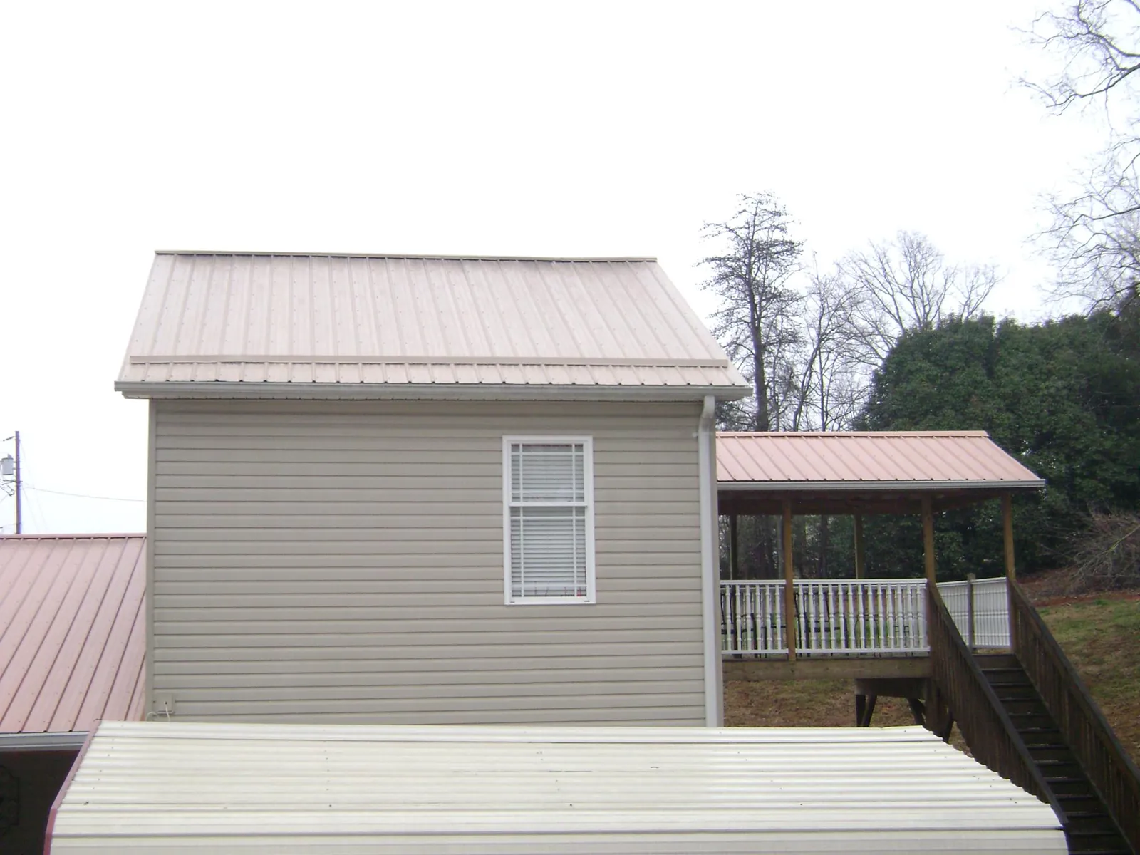 Tan metal roofs on a two story addition and attached porch, from a Roof Replacement job in New Ipswich