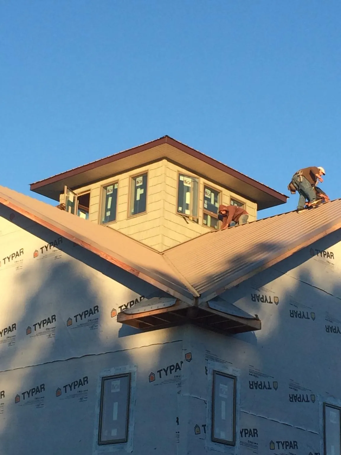 Roofers working around a rooftop cupola on a new metal roof at sunset — Roof Waterproofing in New Ipswich by Roofing Brothers